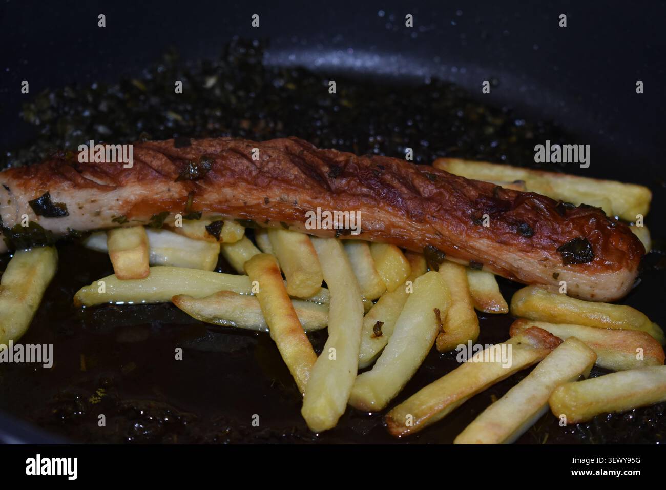 Wurst auf Pommes in einer Pfanne Stockfoto