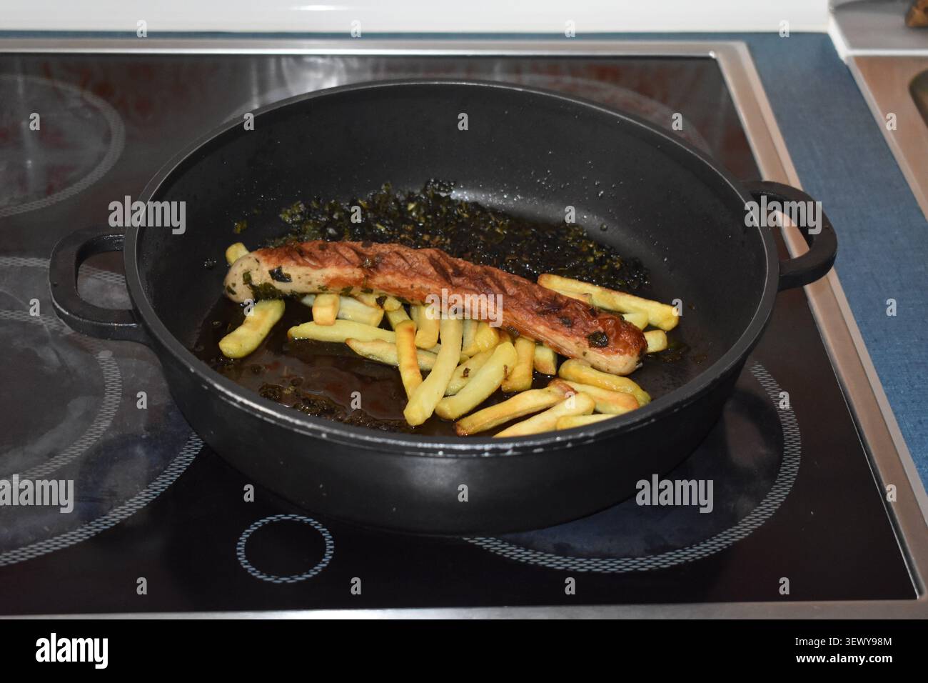 Wurst auf Pommes in einer Pfanne Stockfoto
