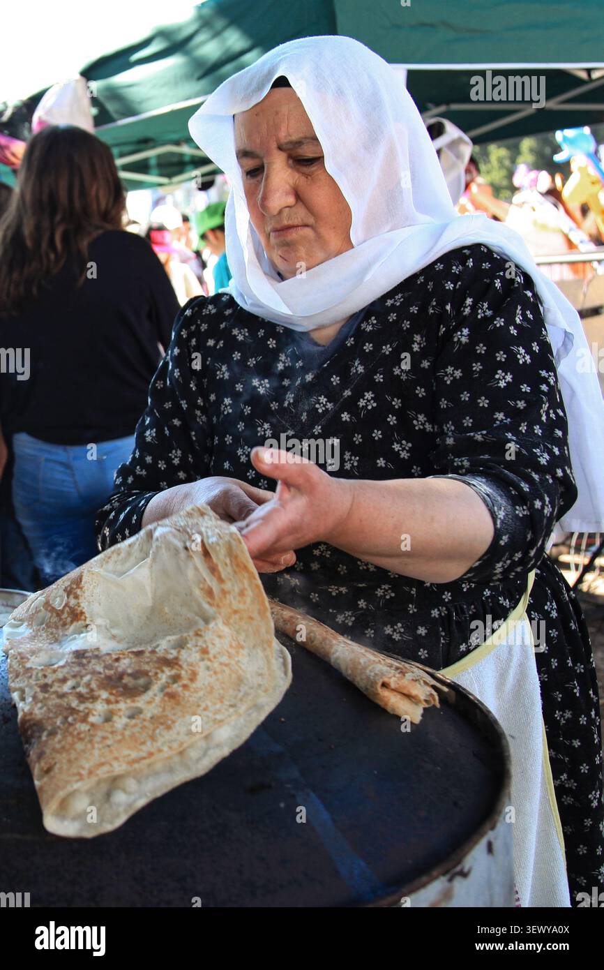 TEL AVIV, ISRAEL - 21. März 2014: Eine Drusenfrau mit traditionellem Kopftuch bereitet dünnes Drusenbrot auf einer konvexen heißen Grillplatte im Nachalat Binyamin zu Stockfoto