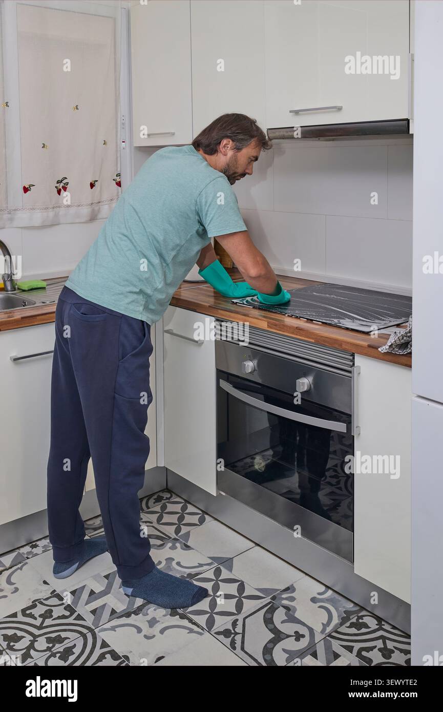 Abwischen des elektrischen Kochfelds mit Schwamm und Tuch während der Hausreinigung. Stockfoto
