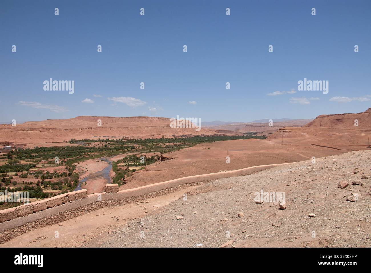 Der weite, trockene Wüstenhorizont, der die Provinz Ouarzazate in Marokko umgibt, erstreckt sich majestätisch unter einem blauen Himmel, der von schroffen Wolken gesäumt ist Stockfoto