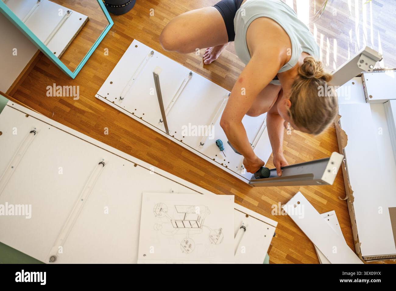Junge Frau, die ein Regal aufbaut, Möbel mit Schraubenzieher zusammenbaut, IKEA Möbel in einer neuen Wohnung, bewegt sich Stockfoto