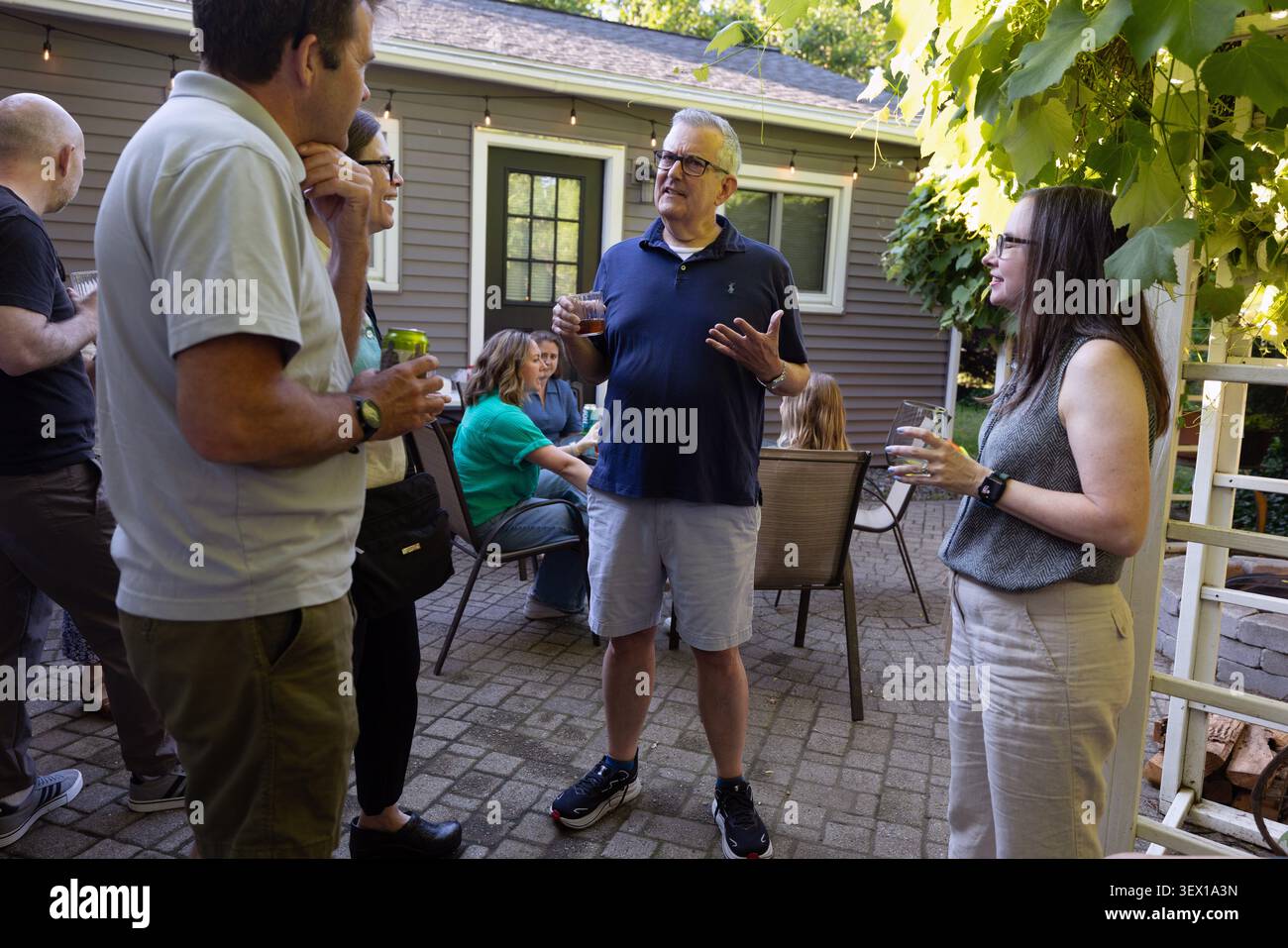 Die Leute unterhalten sich bei einem Treffen im Hinterhof auf einer Wohnterrasse mit Getränken. Stockfoto