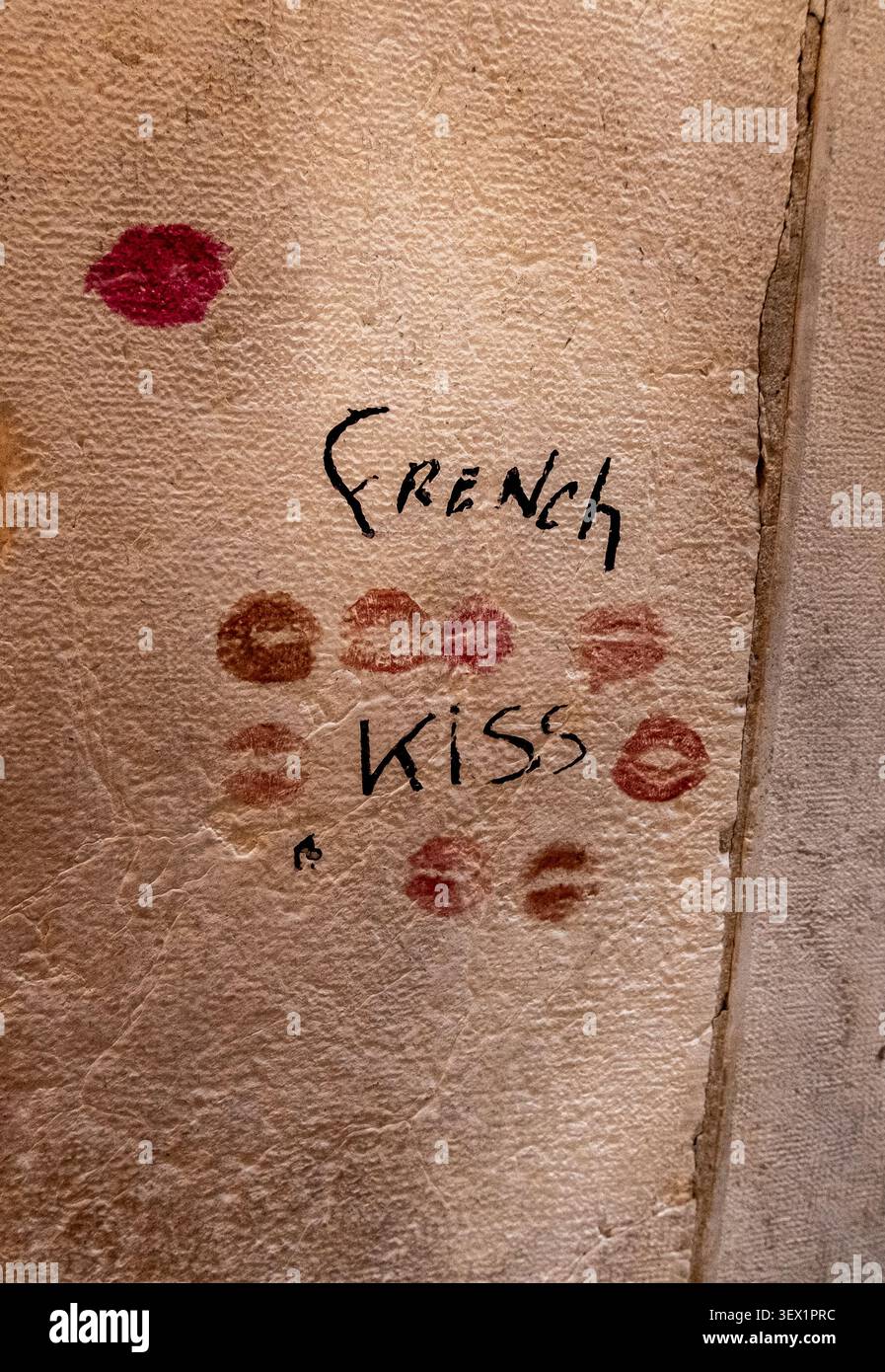 Graffiti mit der Aufschrift „French Kiss“ und Lippenstiftdrucken auf einer texturierten Steinwand Venedig Italien 26. Juni 2026 Stockfoto
