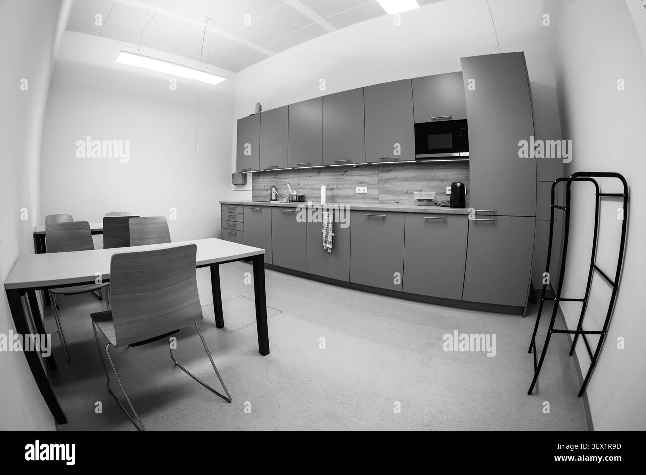 Moderne Büroküche mit Ablageflächen, Tischen und Sitzgelegenheiten. Schwarz-weiß. Stockfoto