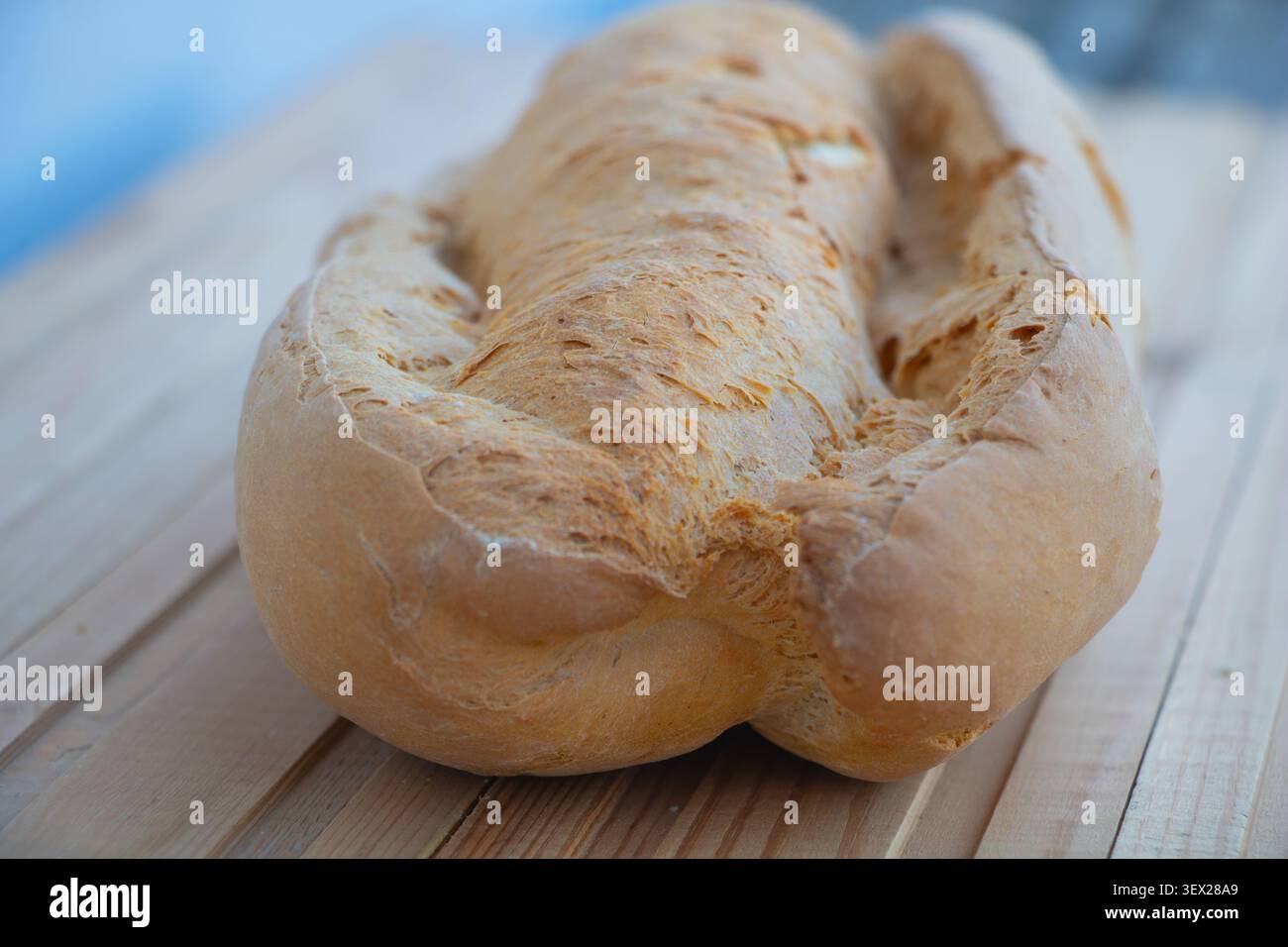 Frisch gebackener rustikaler Brotlaib auf einem Holztisch mit geringer Schärfentiefe. Traditionelles Backwarenprodukt mit goldener Kruste, Stockfoto