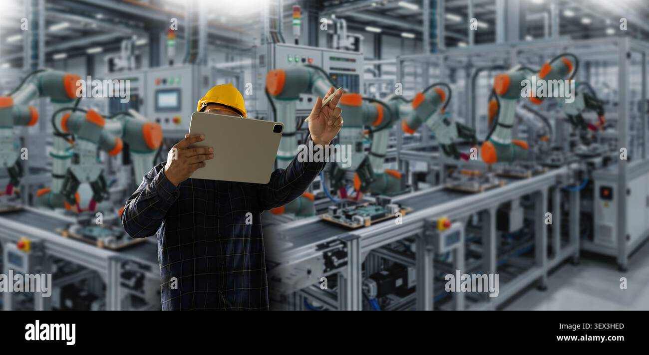 Ingenieure steuern das Tragen eines Schutzhelms verwendet ein Tablet zur Überwachung der Roboterarme in einer Produktionslinie der Fabrik und zeigt die Steuerung der industriellen Automatisierung und Stockfoto