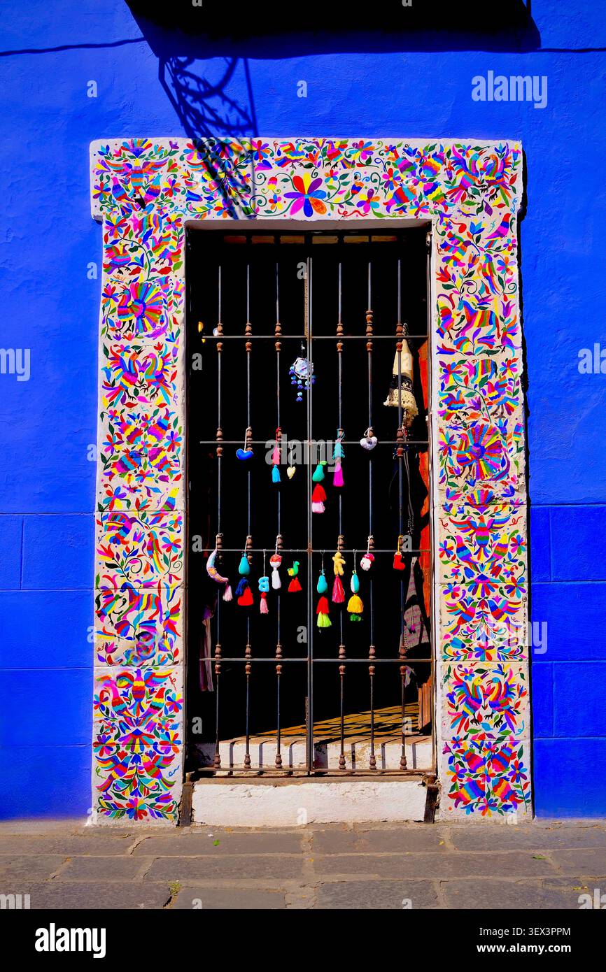 Lackierter Türrahmen mit Quasten an blauer Wand (Puebla, Mexiko) Stockfoto