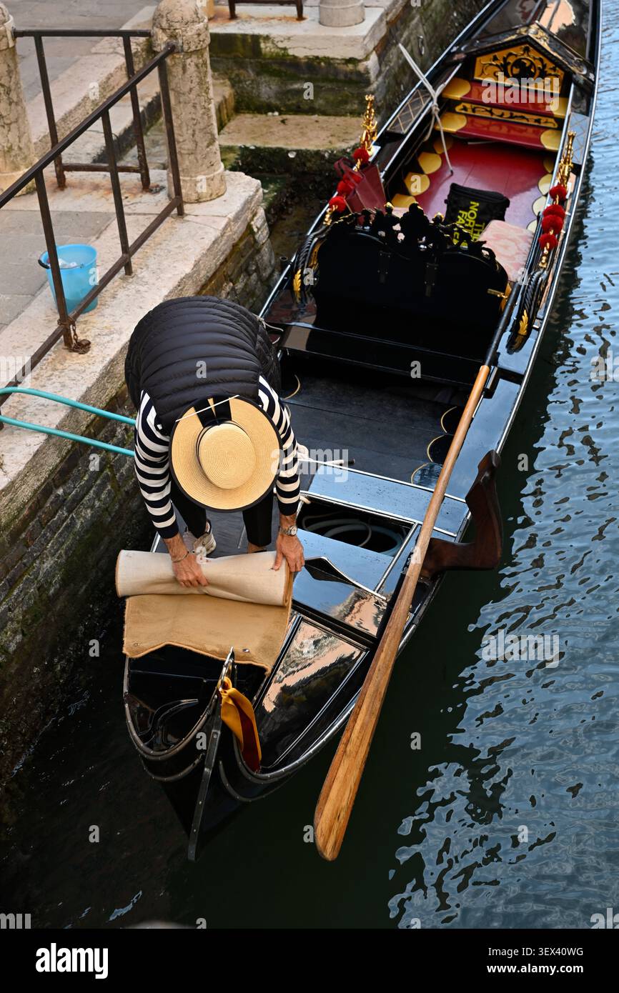 Traditionelle venezianische Gondoliere tragen ikonische gestreifte Hemden und Strohhüte entlang eines kleinen Kanals in Venedig, Italien. Stockfoto