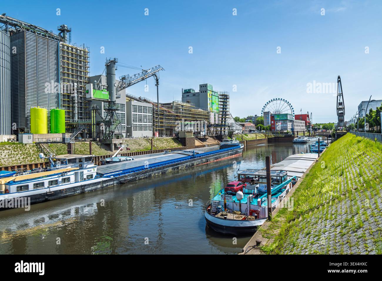 Neuss, Deutschland - 23. Mai 2026: Industriewasserstraße am Rhein mit Lastkähnen und modernen Gebäuden unter klarem blauem Himmel Stockfoto