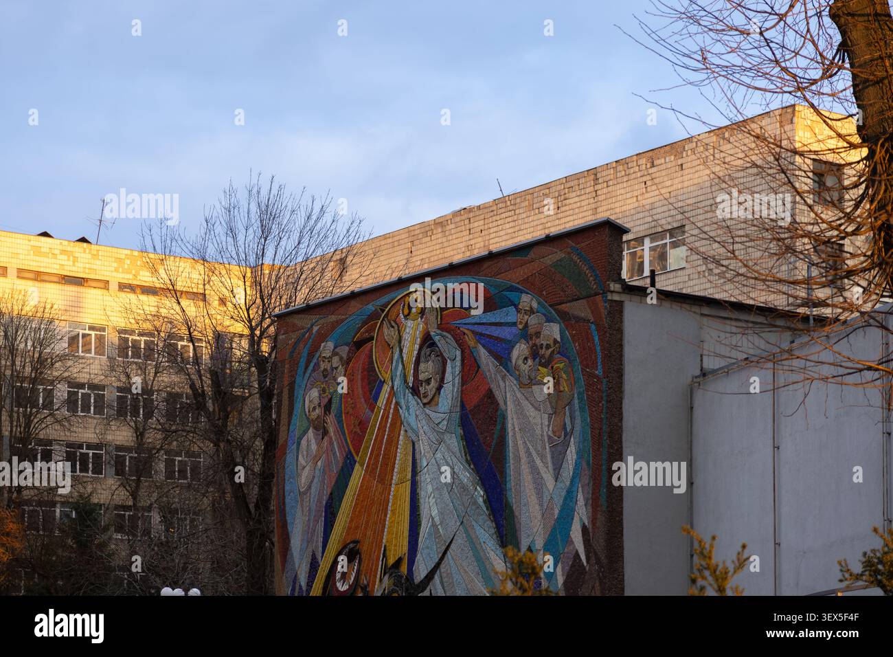 Kiew, Ukraine - 21. März 2026: Komplexe Wandmosaikkunst mit lebhaften Farben zeigt symbolische menschliche Figuren in einer industriellen Umgebung, die Geschichte widerspiegelt Stockfoto