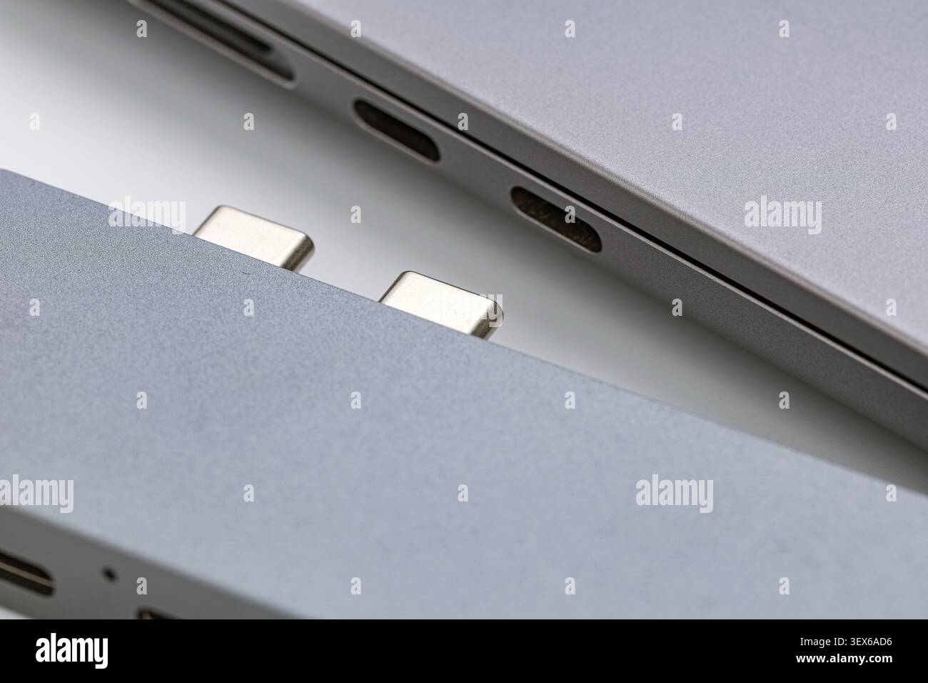 Makroaufnahme zweier moderner tragbarer Aluminiumrechner mit USB-Anschlüssen vom Typ C und metallischen magnetischen Anschlussstiften, die sl hervorheben Stockfoto