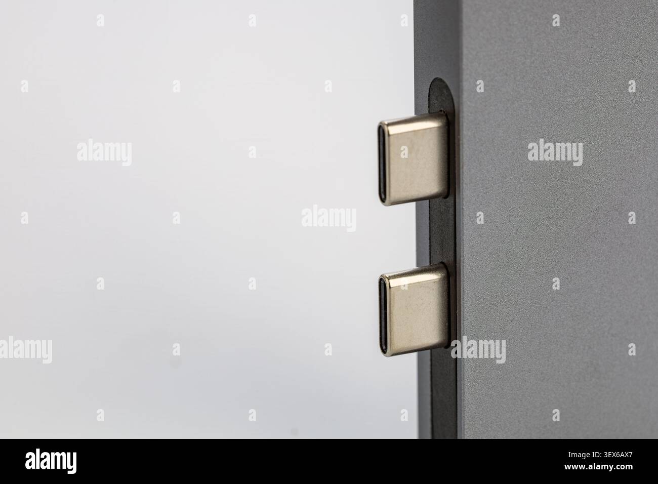 Makroaufnahme von zwei USB-Typ-C-Steckverbindern, die in die Anschlüsse eines schlanken, grauen elektronischen Aluminiumgeräts eingesteckt sind und das moderne, umkehrbare Universalgerät zeigen Stockfoto