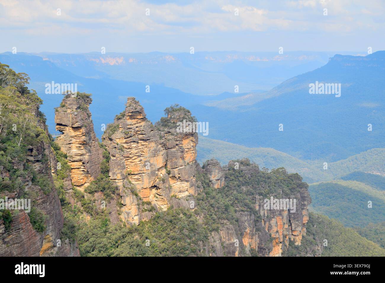 Australien, New South Wales, Katoomba, Blue Mountains National Park, Echo Point Lookout, Three Sisters Felsformation mit Blick auf das Jamison Valley, mit Sandsteinklippen, Eukalyptuswald und bläulichen Bergrücken der Blue Mountains Stockfoto
