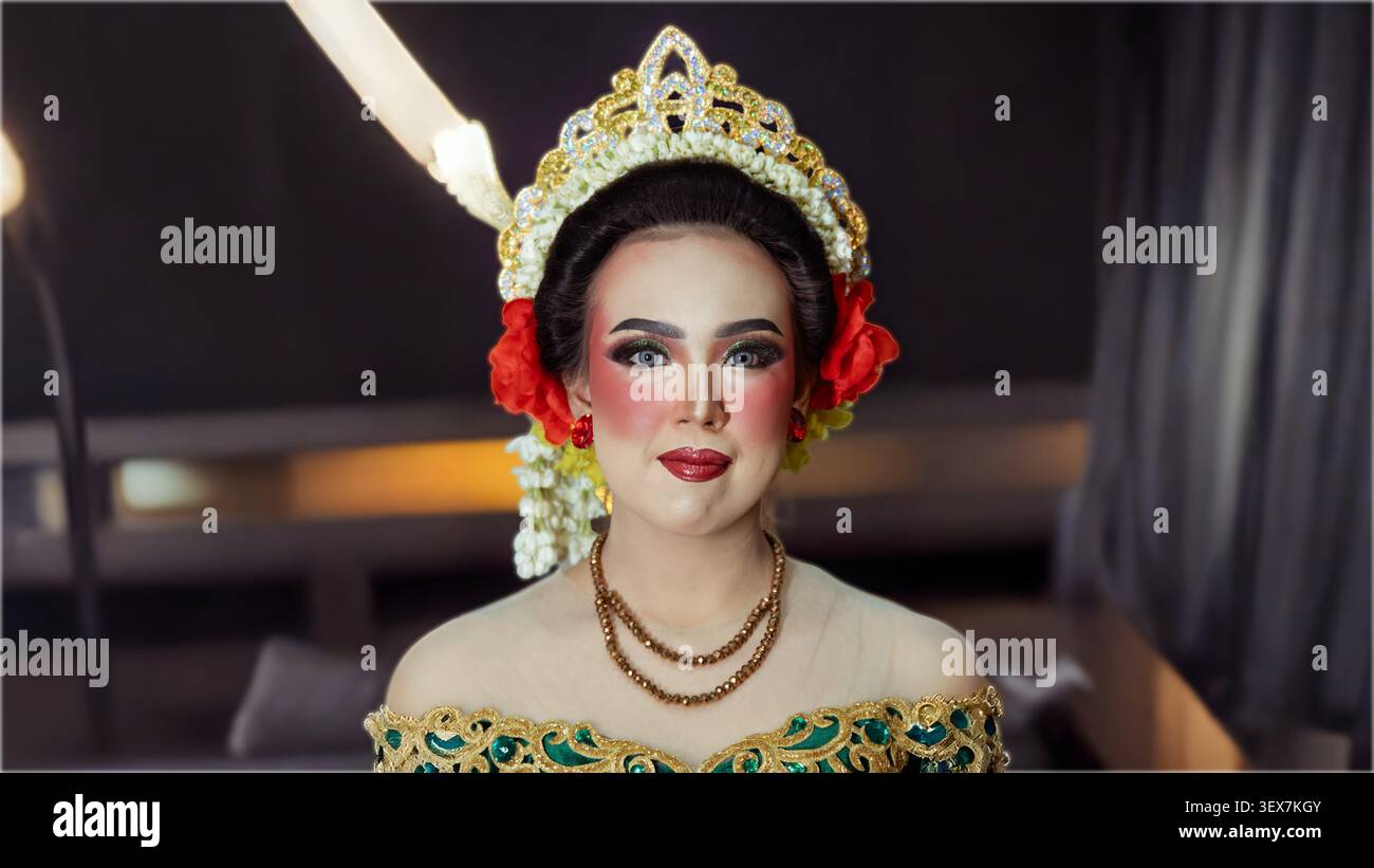 Porträt im Studio-Stil mit indonesischem Braut-Make-up, dekorativer Krone und anmutigem Ausdruck vor verschwommenem Hintergrund. Stockfoto