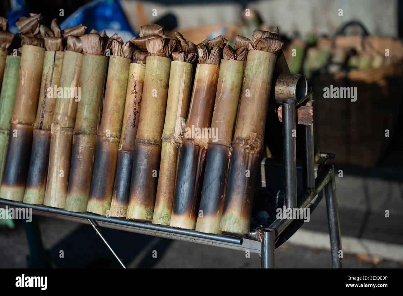 Zubereitung des Desserts Khao Lam oder Lemang, langsam gerösteter klebriger Reis in Bambussprossen über Kohlen Stockfoto