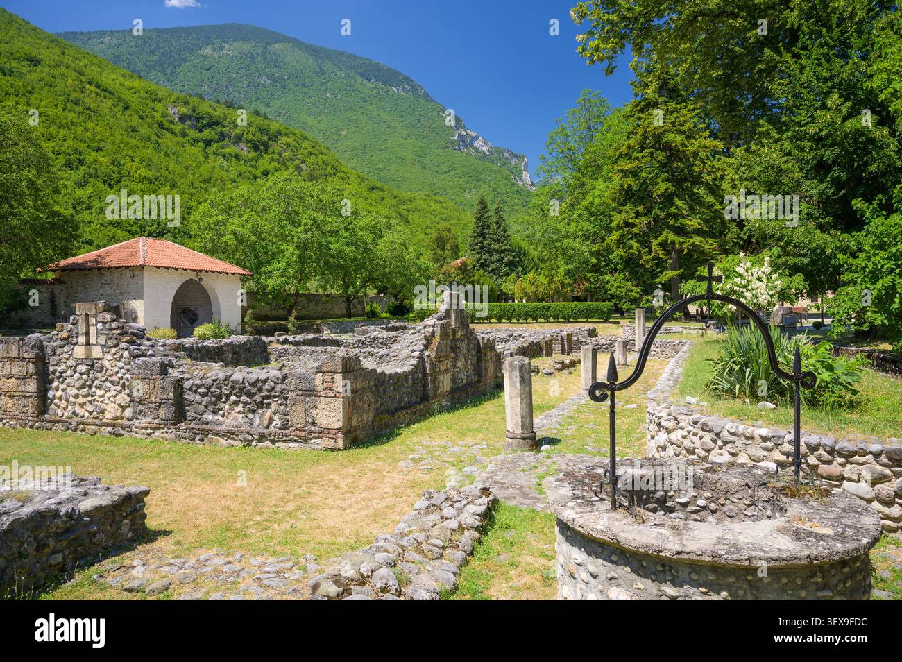 Peja, Kosovo, 28. Juni 2026: Steinruinen mit Eisernen Brunnenkreuz im Patriarchat des Klosters Peć, Kosovo Stockfoto