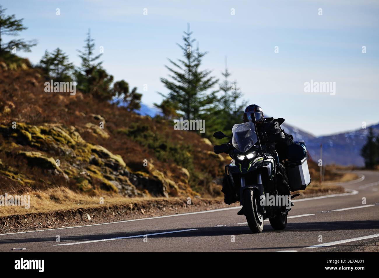 Die schottische Highlands Road Szene in Schottland bietet Motorradfahrer, offene Straßen und immergrüne Bäume. Entfernte Hügel sorgen für Größe und Lage. Stockfoto