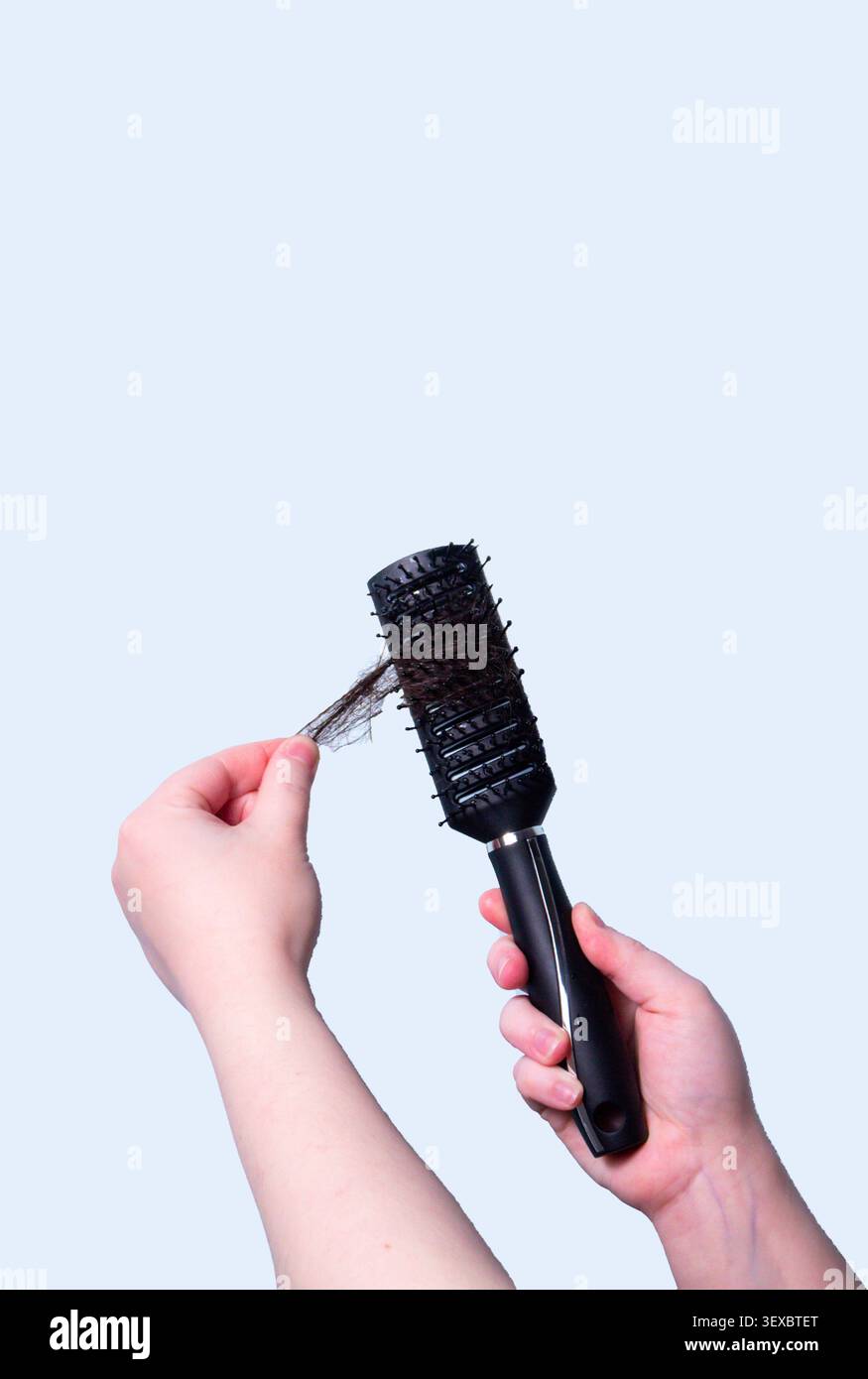 Frau Hand hält Haarbürste und Haarsträhne nach Sturz. Symbol des Haarausfalls. Behandlung und gesundheitsbezogenes Thema. Stockfoto