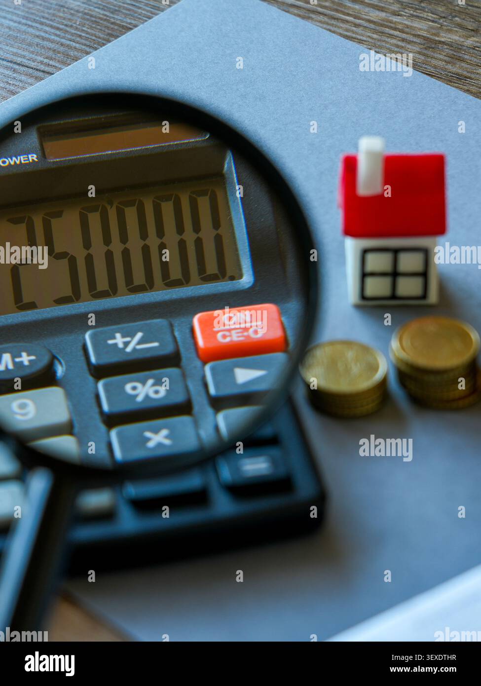 Prüfung der Hypothekenkosten mit Lupe, Rechner, Hausmodell und Ersparnissen für die Planung von Wohnungsdarlehen Stockfoto