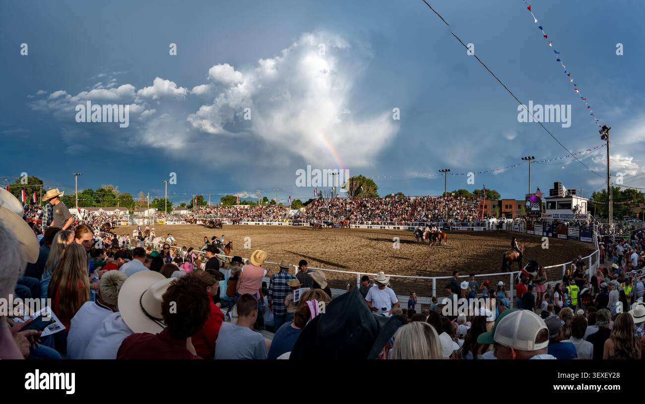 Lehi, USA - 25. Juni 2026: Blick auf das Lehi Roundup Rodeo Gelände mit einem Live-Rodeo-Event, Vieh, Fahrer und Zuschauer unter dramatischem Himmel Stockfoto