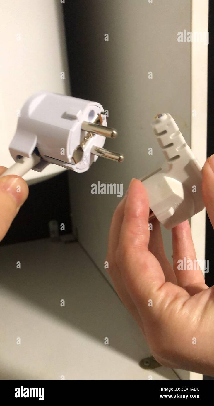 Defekter europäischer Netzstecker in den Händen. Stockfoto