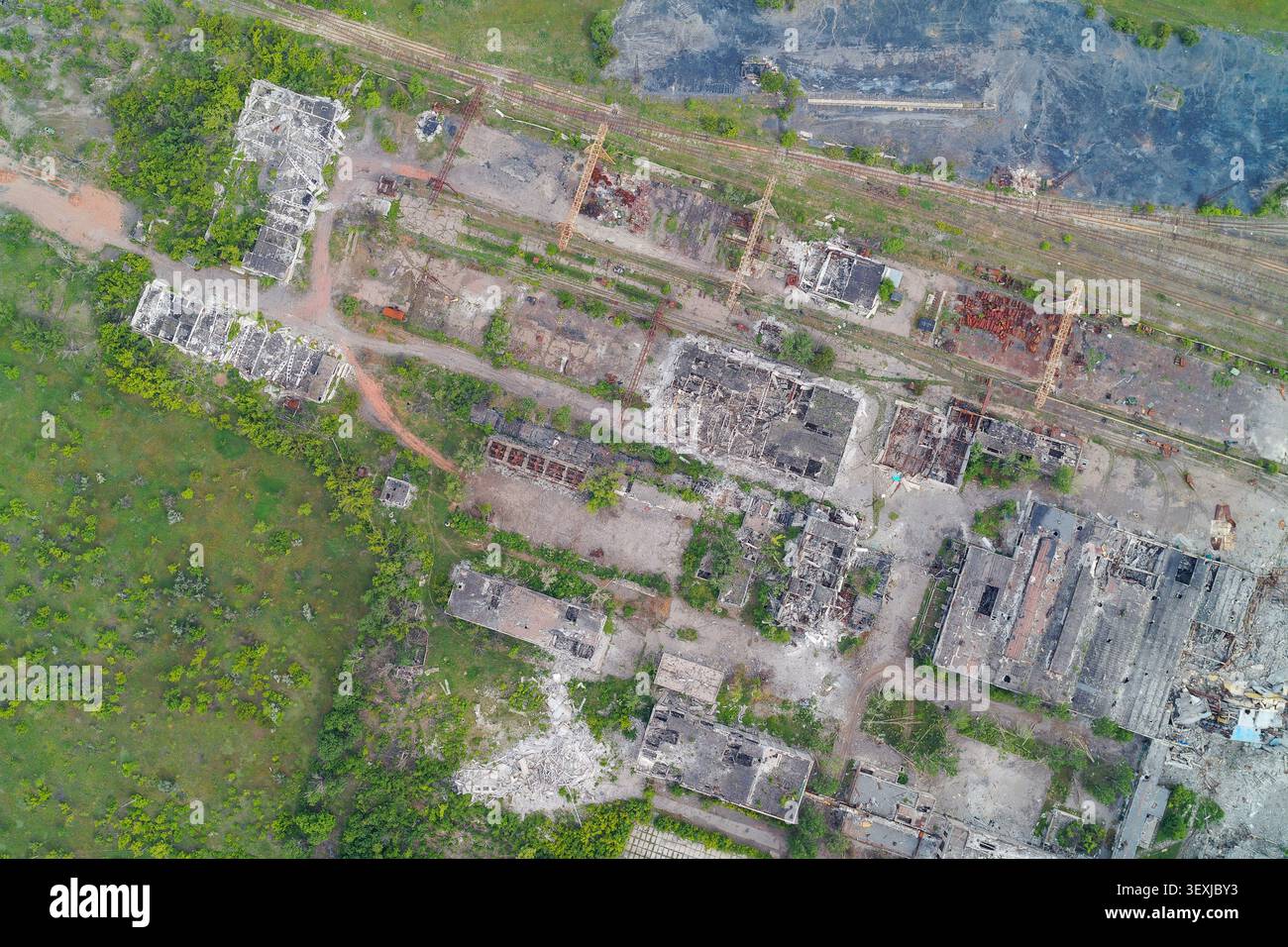 Aus der Vogelperspektive vollständig zerstörte Industrielager und bombardierter Fertigungskomplex. Grafische Darstellung von Infrastrukturschäden, Folgen von Kampfzonen und Verfall von Anlagen. Stockfoto
