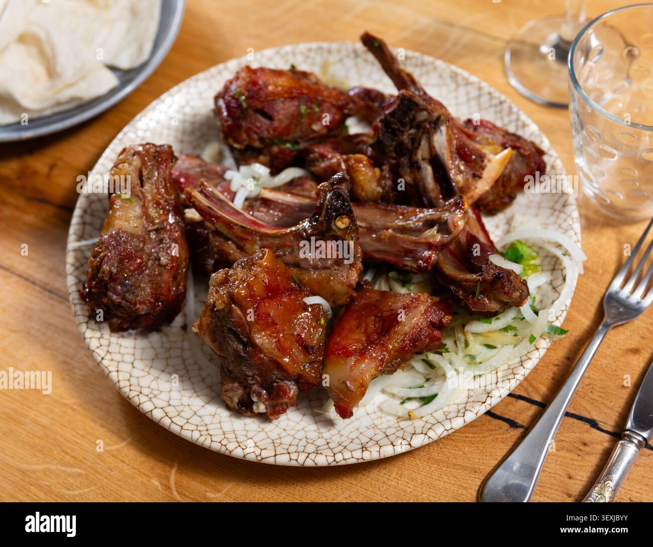Es gibt einen Teller mit gekochtem Lammgrill Schaschlik auf Holztisch. Lammstücke auf offenem Feuer gebraten Stockfoto
