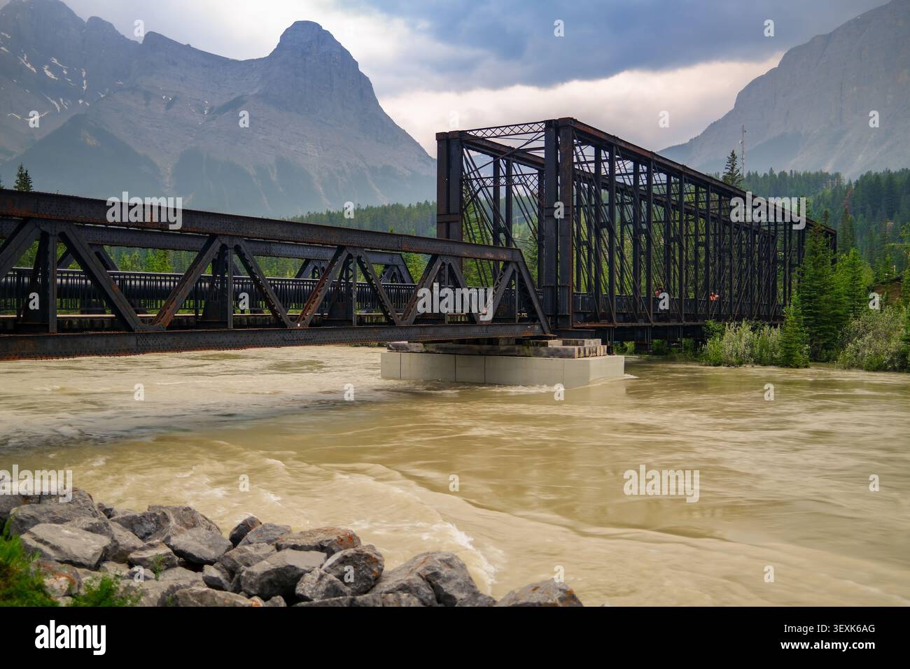 Das geschwollene Raging Bow River trübes Wasser der starke Frühlingsregen überflutete die Pedestrain Pfade an der Engine Bridge in Canmore, Alberta Foothills, den kanadischen Rocky Mountains Stockfoto