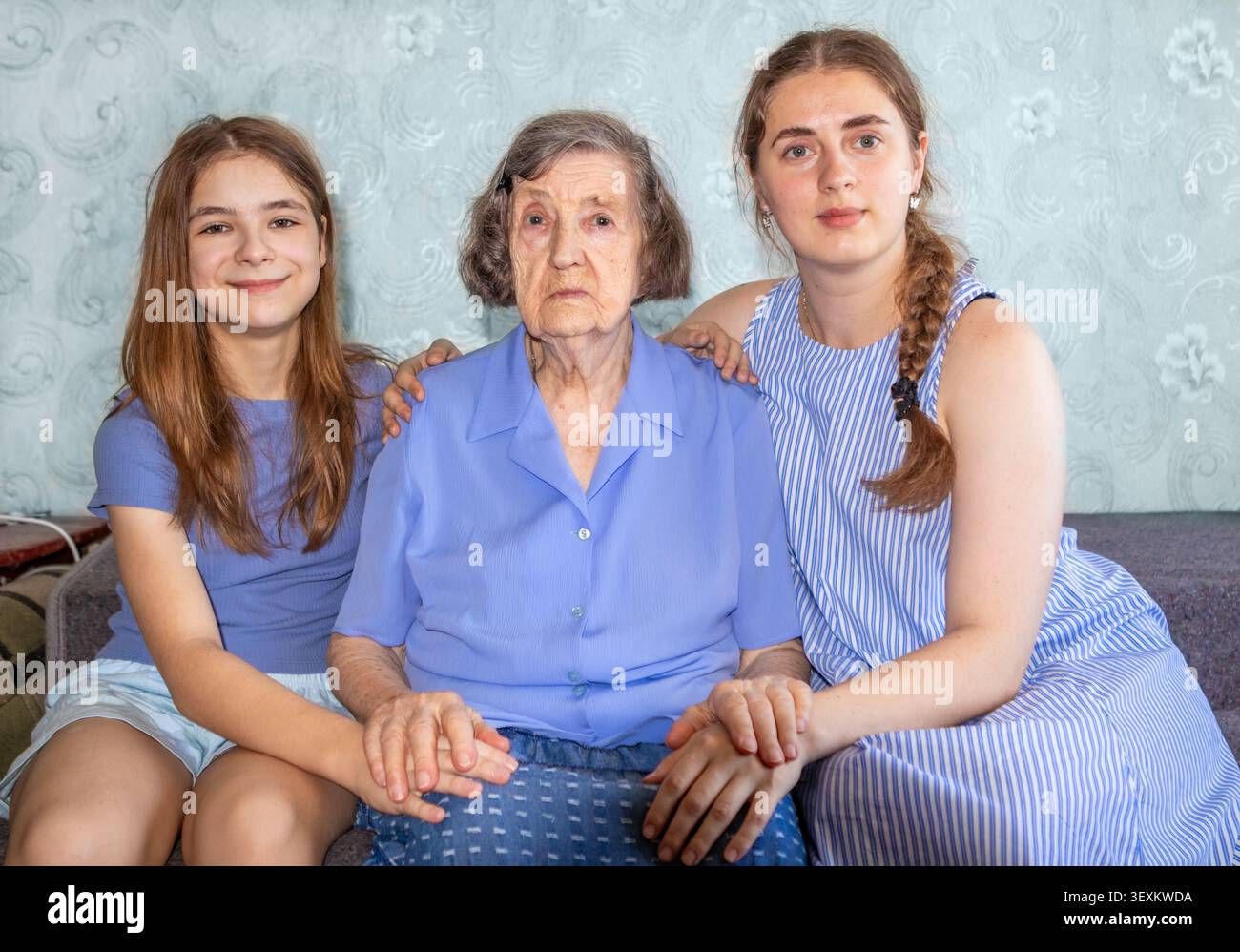 Großmutter mit zwei Enkelinnen, die auf einer Couch sitzen und Unterstützung und Zuneigung zeigen Stockfoto