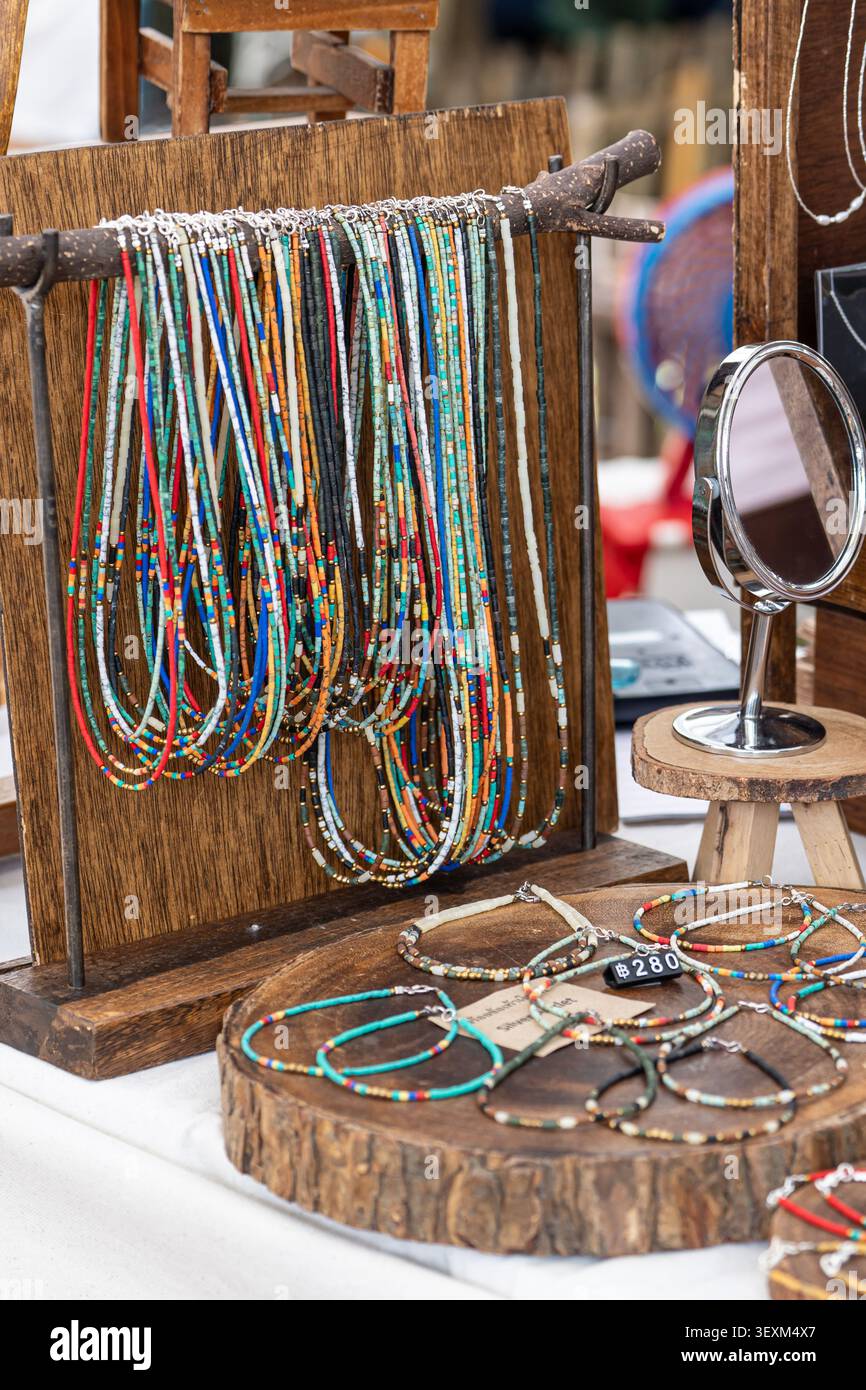 Bunte Ketten und Armbänder mit Samenperlen auf einem Holzstand an einem Handwerksstand Stockfoto