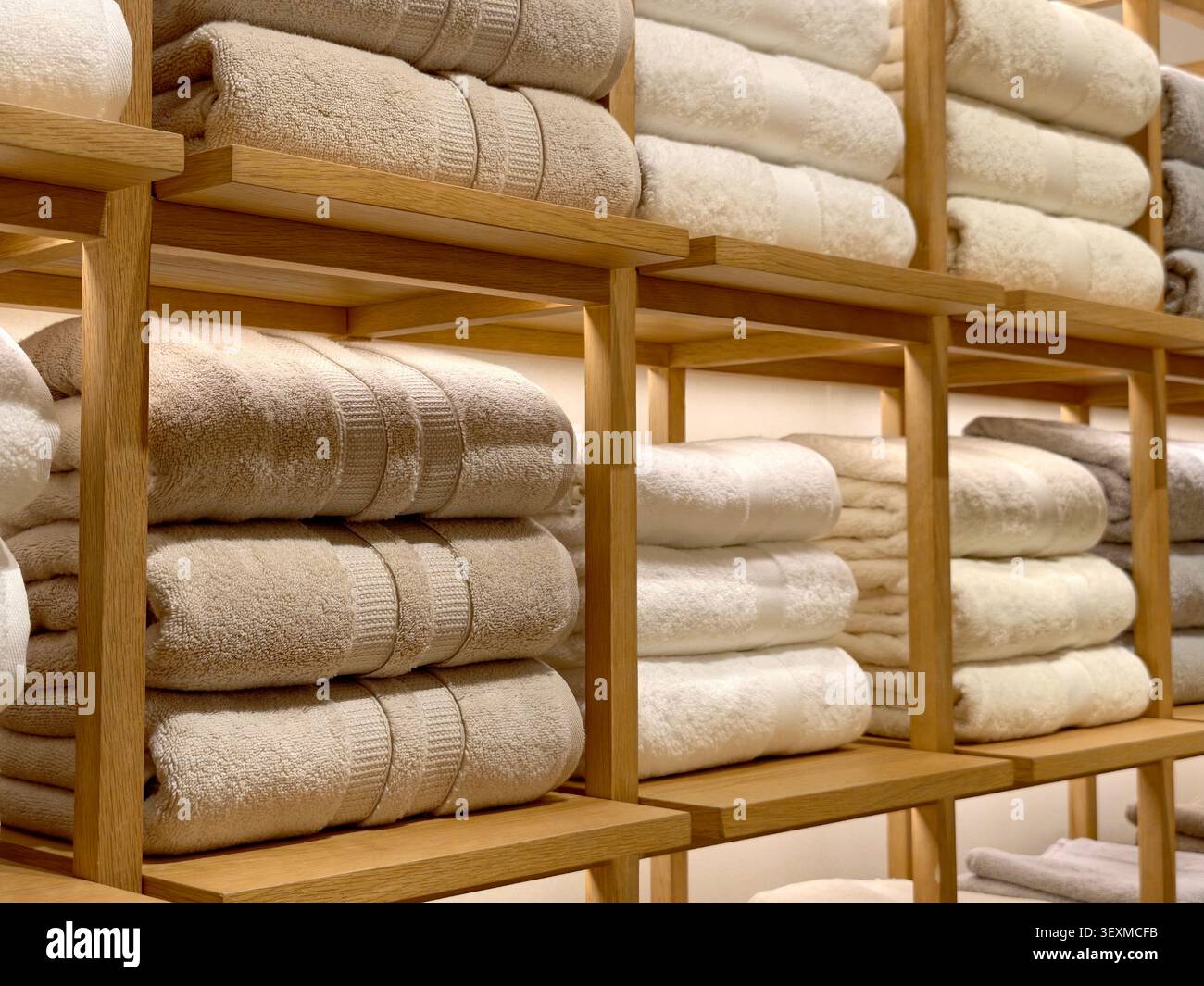 Ordentlich gefaltete beige und weiße Handtücher auf Holzregalen Stockfoto
