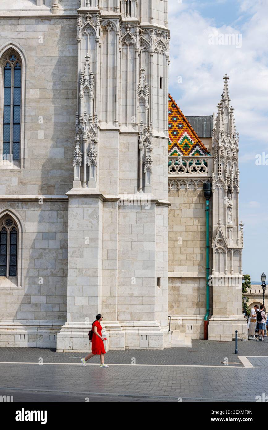 Frau in Rot, die an der Kirche unserer Lieben Frau von Buda vorbeigeht, Budapest, Ungarn Stockfoto