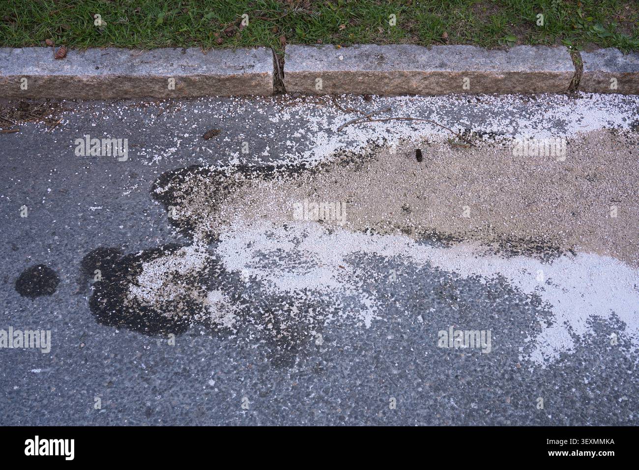 Ölflecken in Oslo, Norwegen. Bodenverschmutzungsproblem. Ölleckage wird durch absorbierende Katzenstreu auf der Fahrbahn neutralisiert. Stockfoto