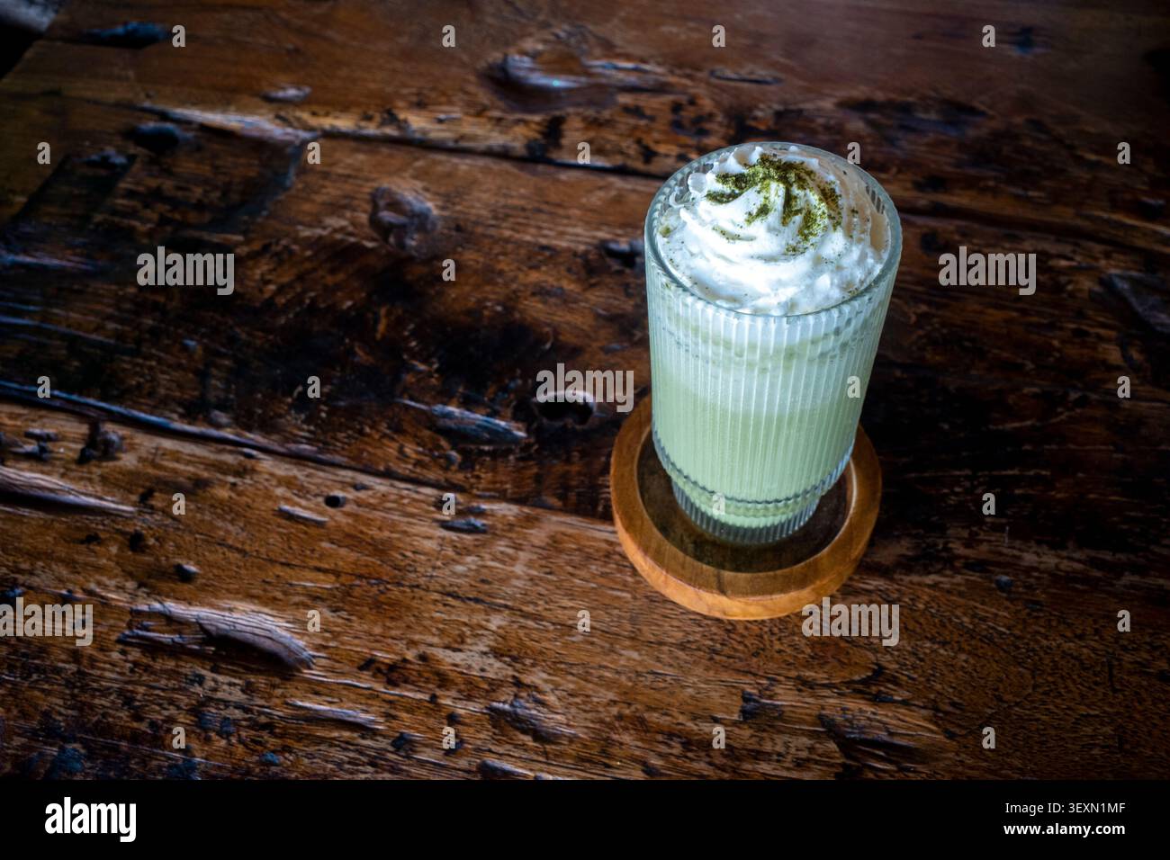 Ein Glas Matcha Green Tea Milchshake, garniert mit einem Keks und weißer Pasta. Stockfoto