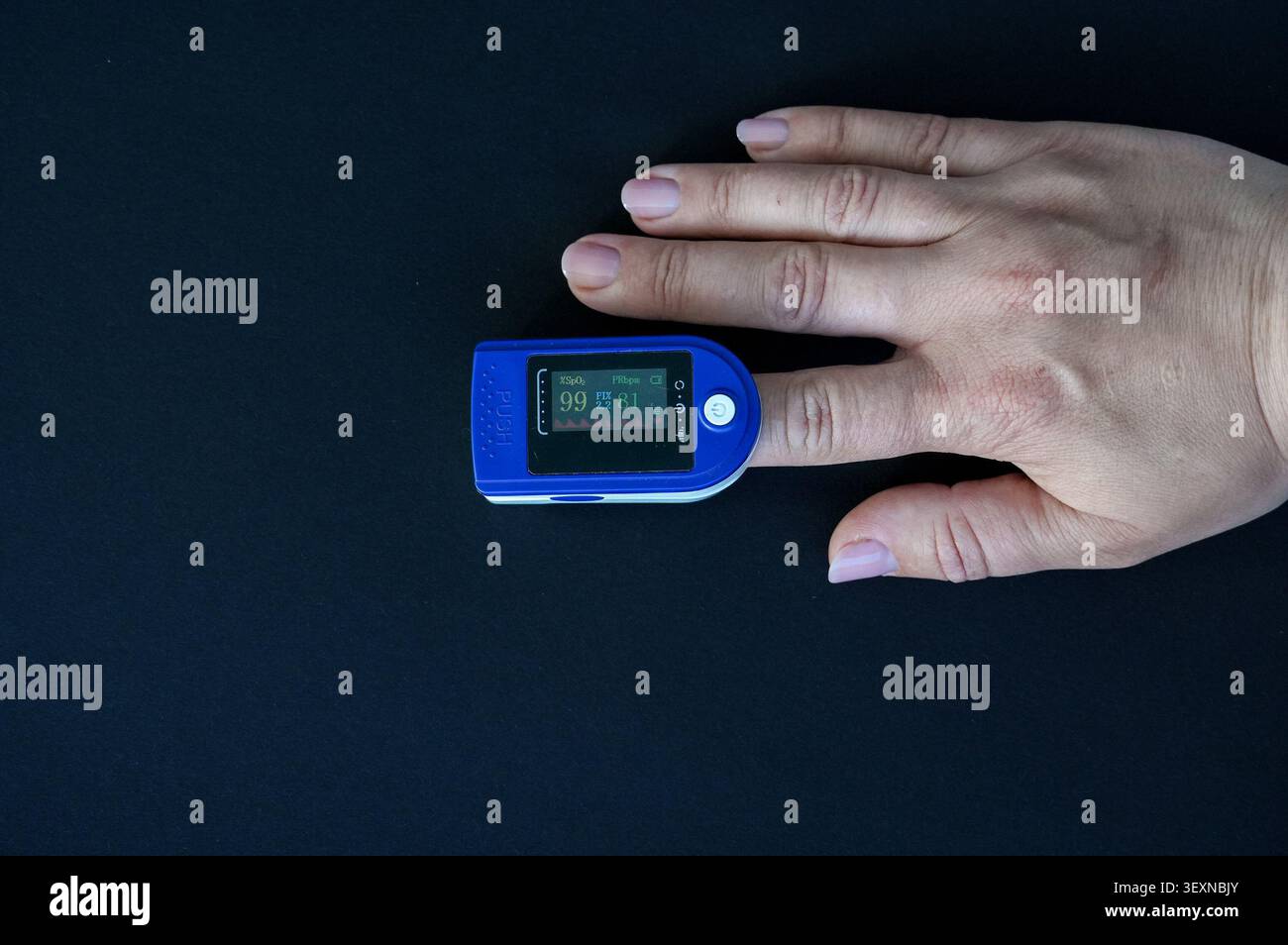 Hand mit Pulsoximeter isoliert auf schwarzem Hintergrund. Medizinische Ausrüstung. Stockfoto