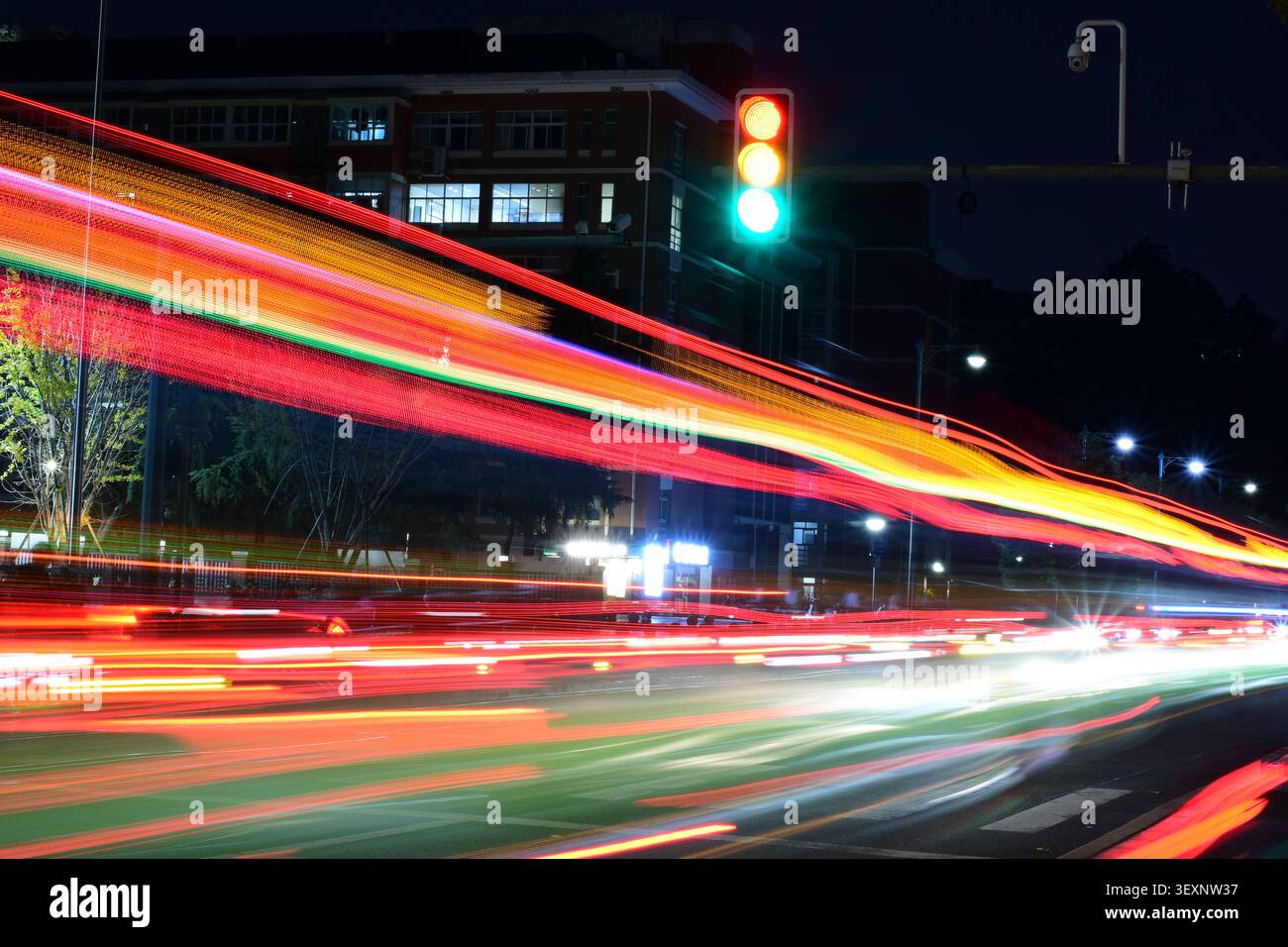 Langzeitbelichtung, die lebhafte rote und orangefarbene Fahrzeuglichtstreifen auf einer Nachtstraße einfängt Stockfoto