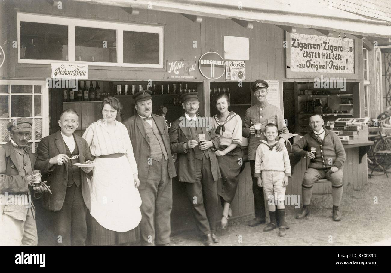 Pub, Taverne, Imbiss, Zigarren, Geschäft, Geschäft, Beruf, Zwanziger, eine Gruppe von Leuten, die trinken und posieren, lächelnd vor einem Zigarrenladen, gegen 19 Stockfoto