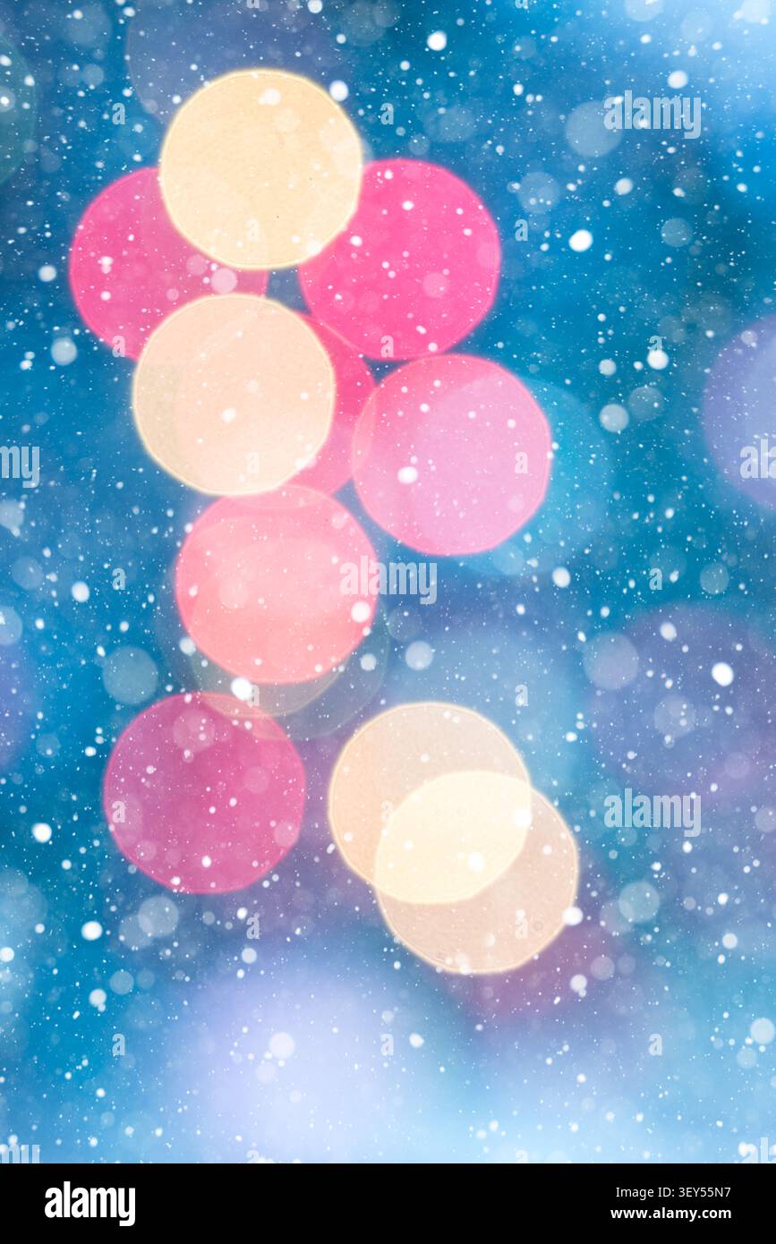 Vertikaler abstrakter festlicher Hintergrund mit roten und goldenen Bokeh-Lichtern auf einem tiefblauen Hintergrund mit sanft fallenden Schneeflocken. Warmes Leuchten Stockfoto