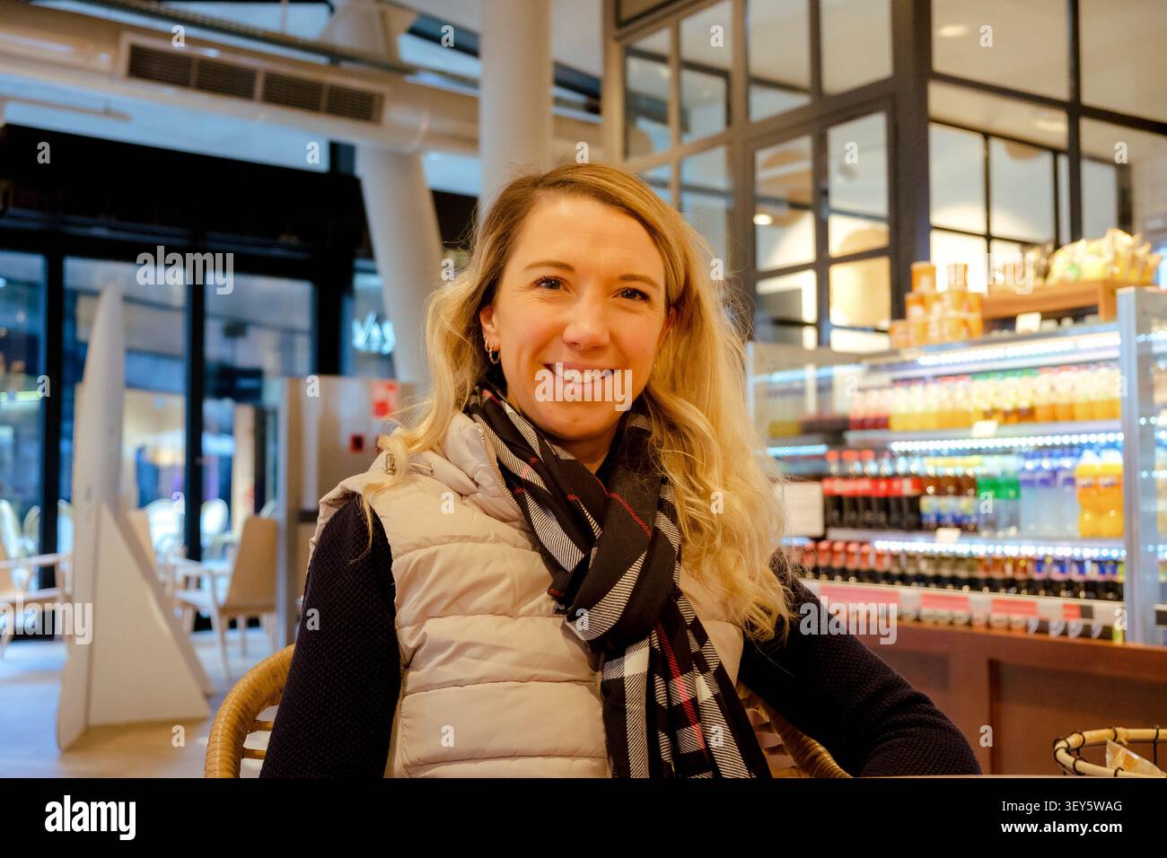 Lächelnde Frau genießt eine Pause und Erfrischung in einem modernen Flughafencafé Stockfoto