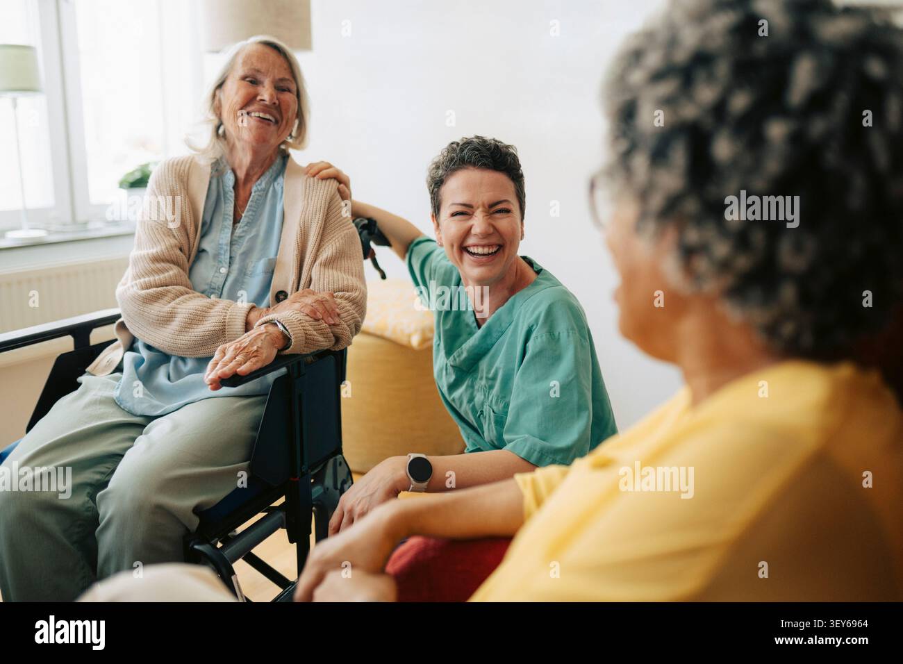 Glückliche Krankenschwester, die Spaß mit Seniorinnen im Altersheim hat Stockfoto