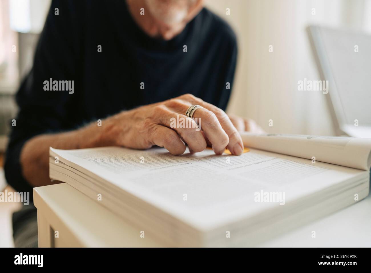 Nahaufnahme eines älteren Mannes, der in seiner Freizeit Bücher im Altersheim liest Stockfoto