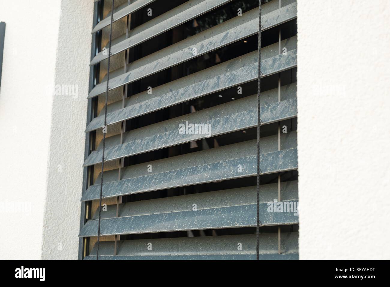 An der Außenseite eines modernen Wohngebäudes sind Fensterläden aus langlebigen Materialien installiert. Die Rollläden ermöglichen Belüftung, während Privatsphäre und Ästhetik erhalten bleiben. Stockfoto
