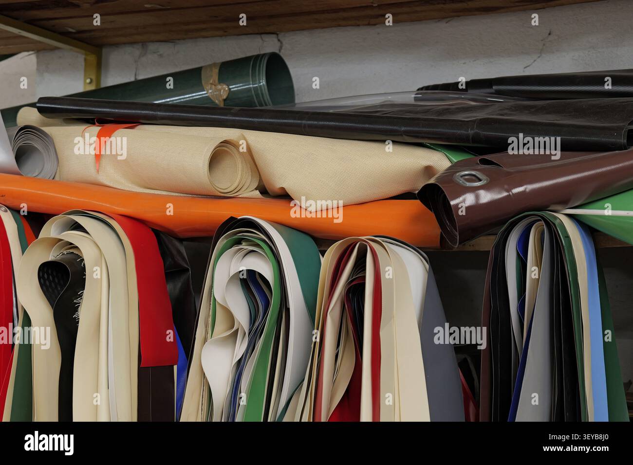 Lagerung von verschiedenfarbigen Rollen aus strapazierfähigem, wasserdichtem Planen-, Leinwand- und Vinylgewebe in Regalen, die den Materialbestand eines Herstellers darstellen Stockfoto