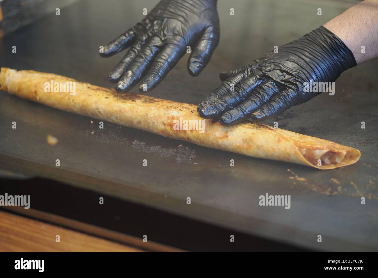 Die Hände bereiten eine lange türkische Dönerpackung vor, die häufig in Straßenrestaurants zu finden ist. Stockfoto