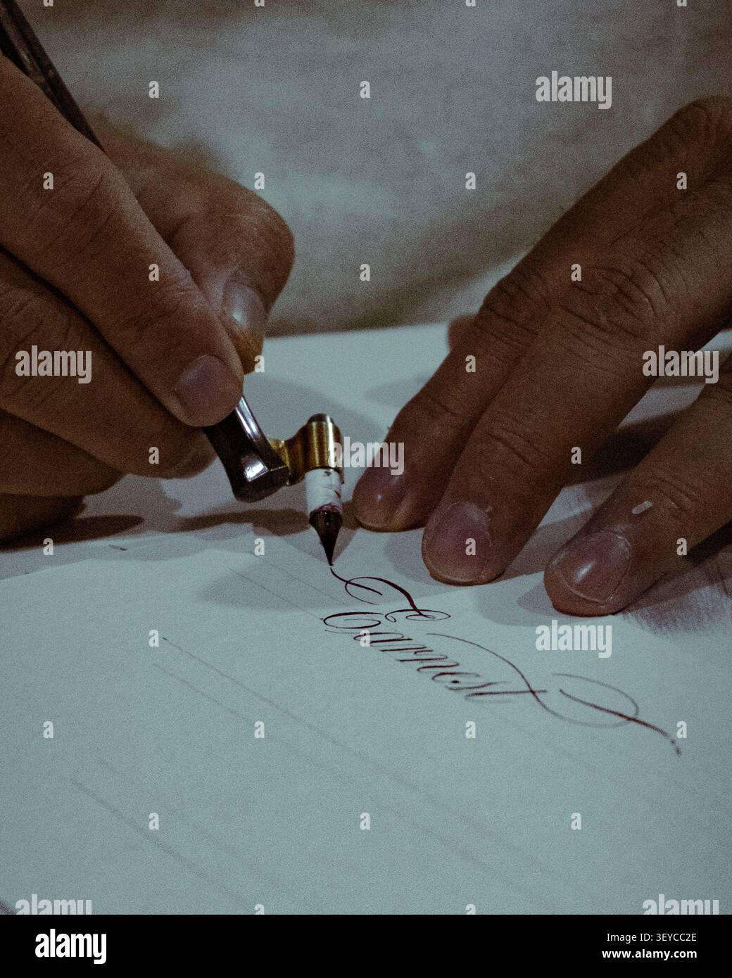 Nahaufnahme eines Kalligraphen, der während einer modernen Kalligraphiepraxis mit Dip Pen und Tinte elegante Handschriften auf Papier schreibt Stockfoto