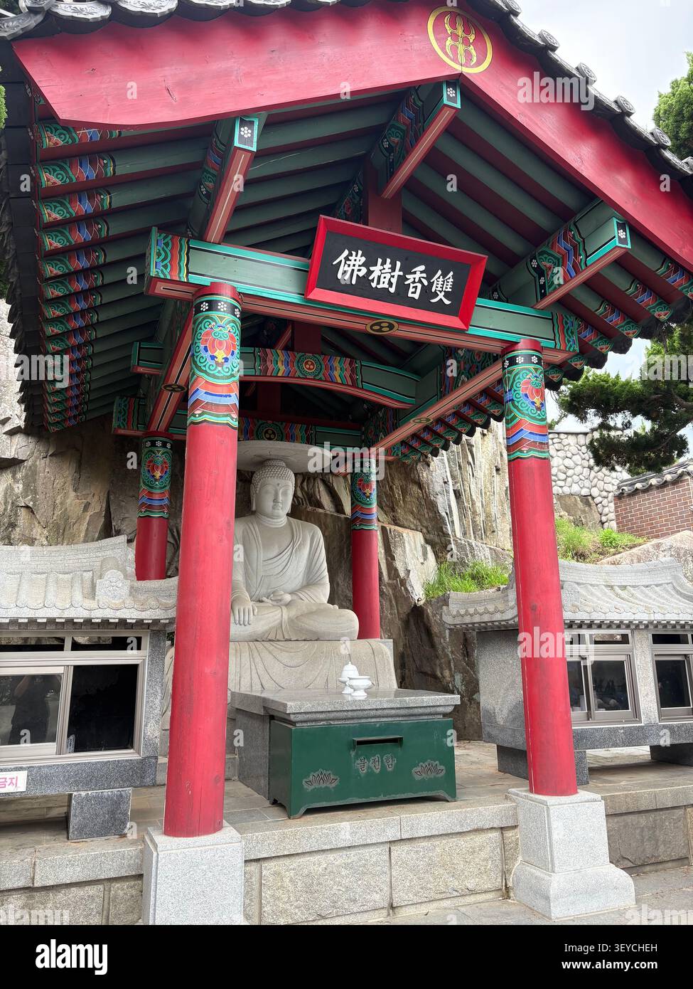 15. Juli 2025, Busan, Südkorea - traditionelles koreanisches buddhistisches Tempeltor mit roten Säulen, verzierten Danceong-Anstrichen, Hanja-Inschrift und W - Smartphone-aufgenommenes Stockfoto