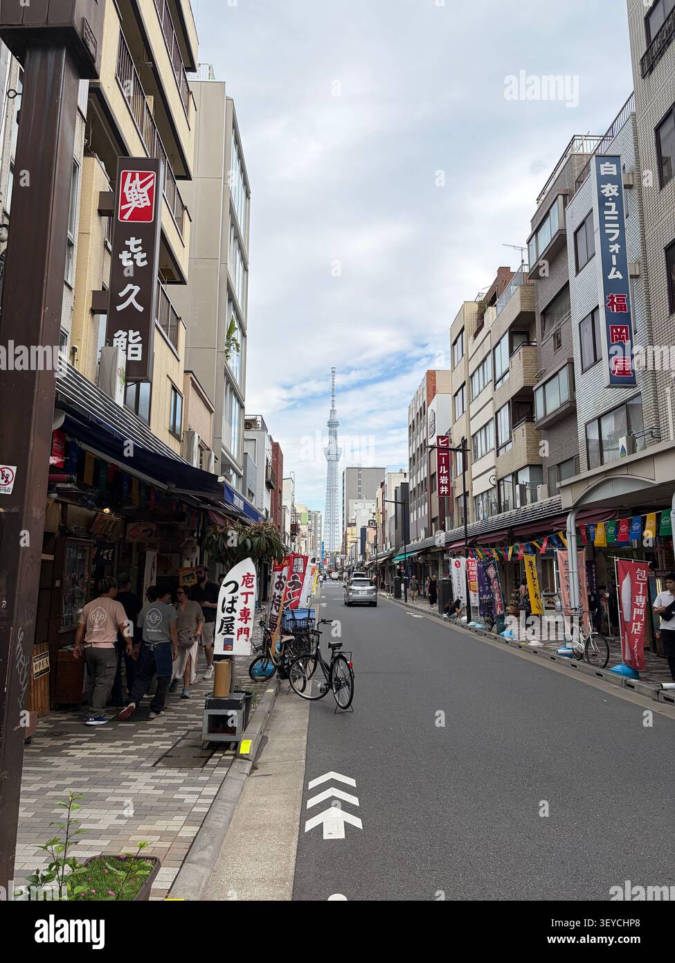 Lebhafte Fußgängerzone im Shinsekai-Viertel, Osaka, Japan, mit Tsutenkaku-Turm im Hintergrund und japanischen Kanji-Ladenschildern. - Smartphone-aufgenommenes Stockfoto