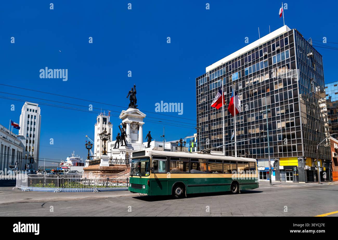 Ein alter grüner Trolleybus fährt am Denkmal der Helden von Iquique an der Plaza Sotomayor in Valparaiso, Chile, vorbei. Stockfoto