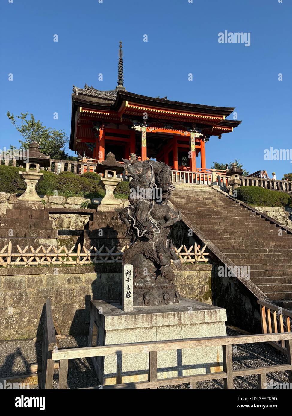 Verzierte Bronze-Drachen-Skulptur im Vordergrund mit kupferfarbenem mehrstöckigem Pagode-Tor am Kiyomizudera-Tempel, UNESCO-Weltkulturerbe, Kyoto, Japan. - Smartphone-aufgenommenes Stockfoto